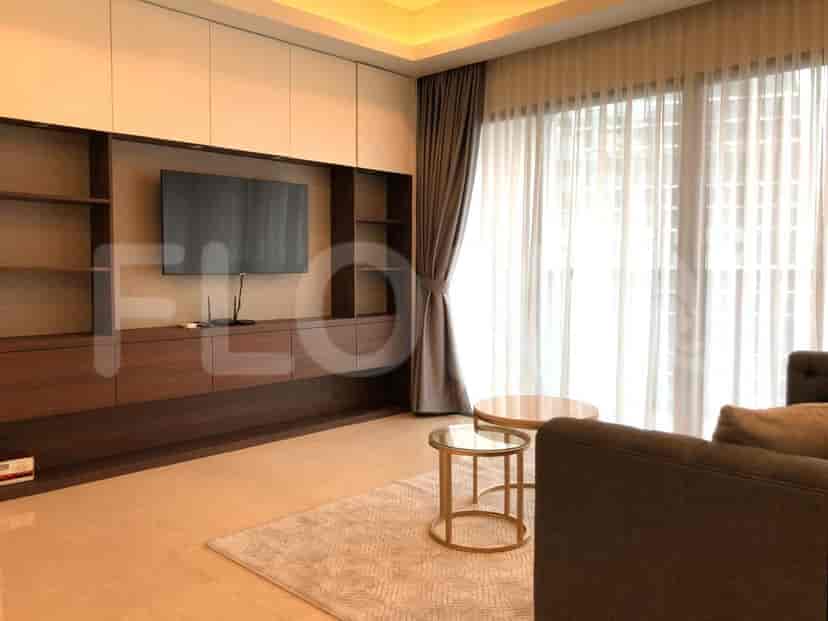 A living room with a wall unit, TV, sofa, and round tables.