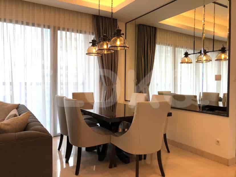 A dining area with a dark wooden table, chairs, and chandelier lighting.