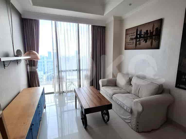 A living room with a sofa, wooden table, and large windows.