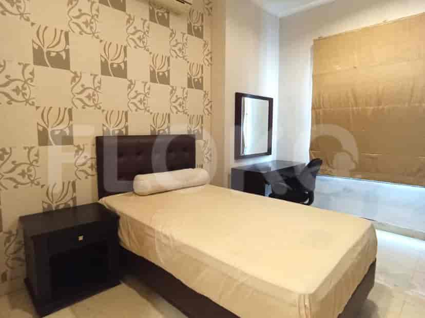 A bedroom with a bed, a desk, and a nightstand.