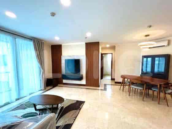A bright and spacious living room with a dining area, TV, and large windows.