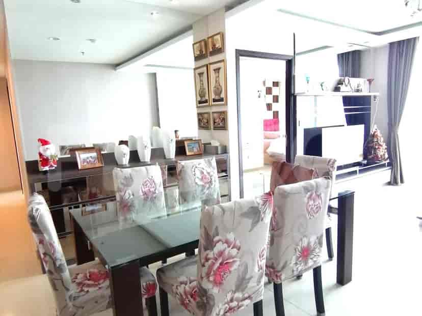A dining room with a glass-top table and floral-patterned chairs.