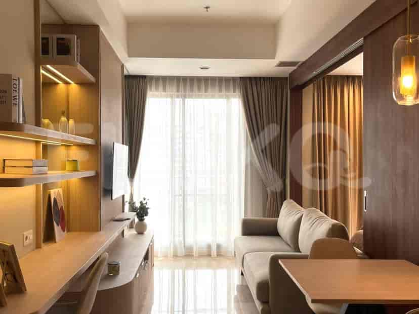 A living room with a beige sofa, desk, and large window.