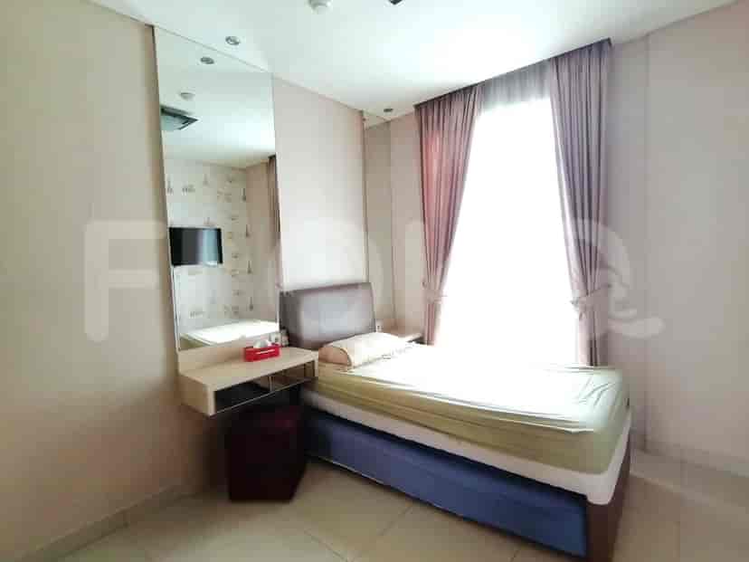 A bedroom with a single bed, a dressing table, and a large window.