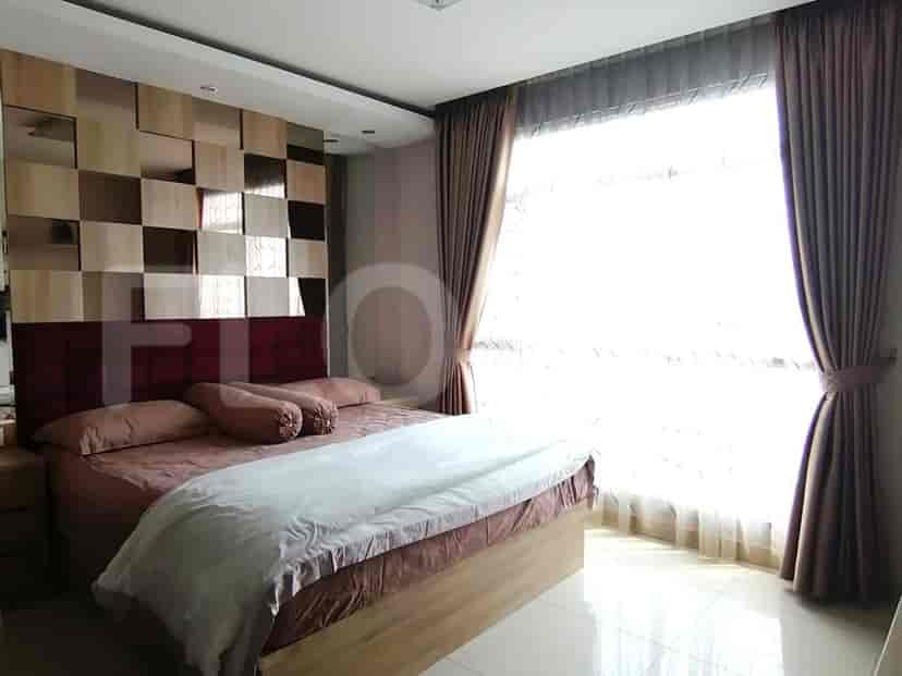 A bedroom with a large bed, wooden floors, and curtains.