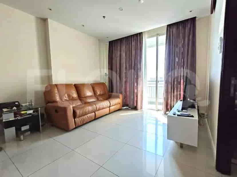 Living room with a brown leather sofa, a TV, and a window with curtains.