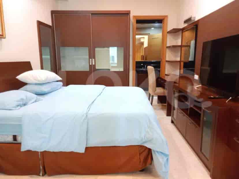 Kamar tidur dengan tempat tidur, lemari built-in, dan area rias/meja.