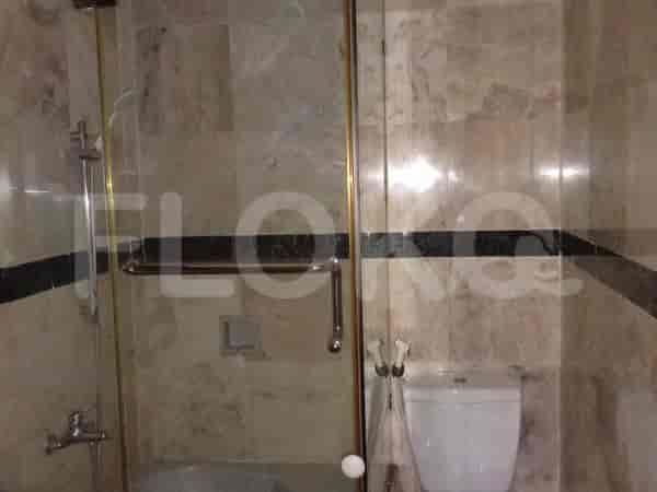 Kamar mandi dengan pancuran kaca, dinding berubin, dan toilet putih.