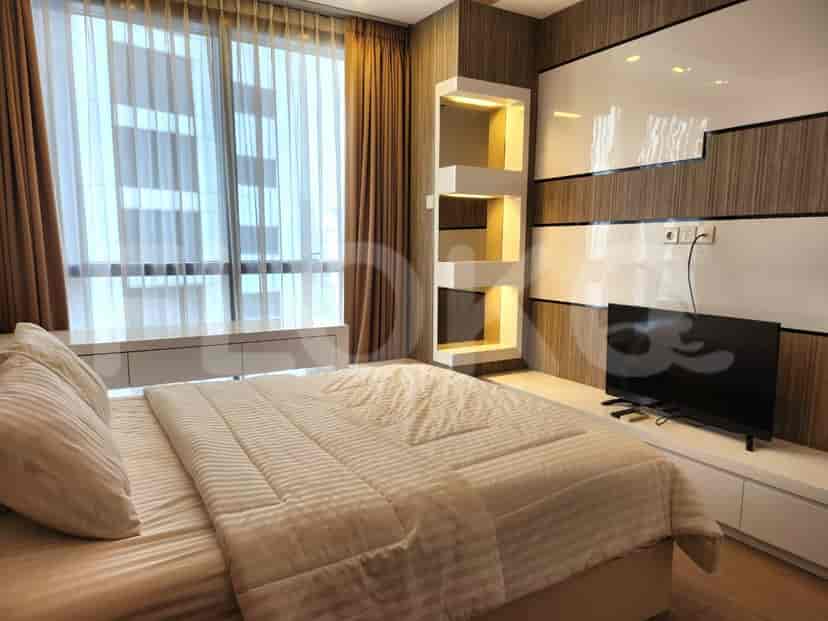 A modern bedroom with a bed, TV, and built-in storage.
