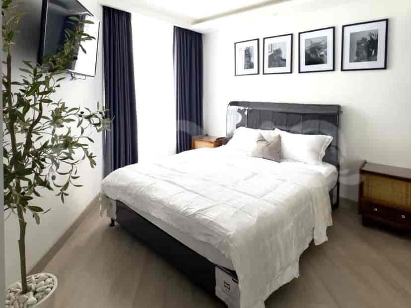 A bedroom with a bed, nightstands, and framed pictures.