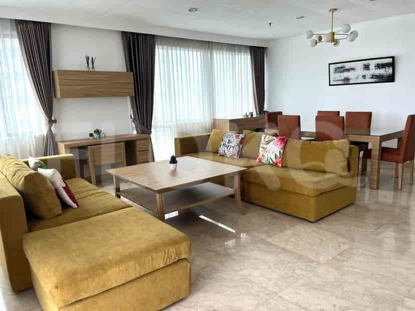 Living room featuring yellow sofa, coffee table, dining table, and large windows.