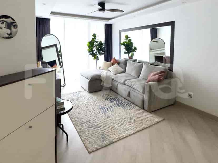 A living room with a grey sofa, a rug, a mirror, and plants.