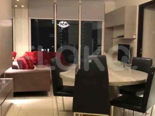 A modern living room with a round dining table and a red sofa, offering a city view.