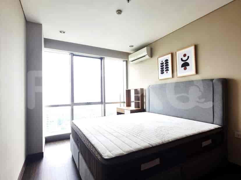 A bedroom with a bed, side table, and artwork next to a large window.