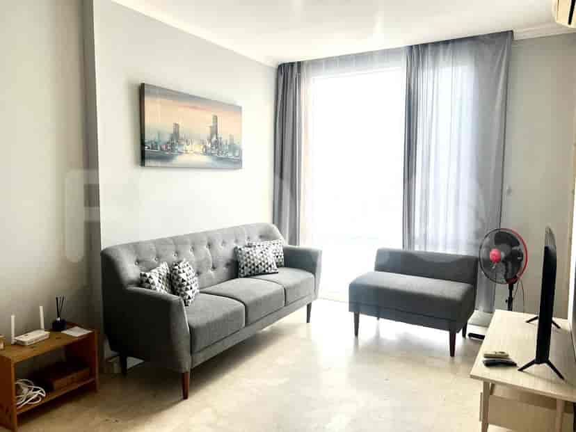 Ruang tamu yang terang benderang dengan sofa abu-abu, seni, dan jendela besar.