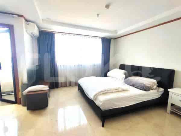 A well-lit bedroom with a bed, curtains, and a bedside table.