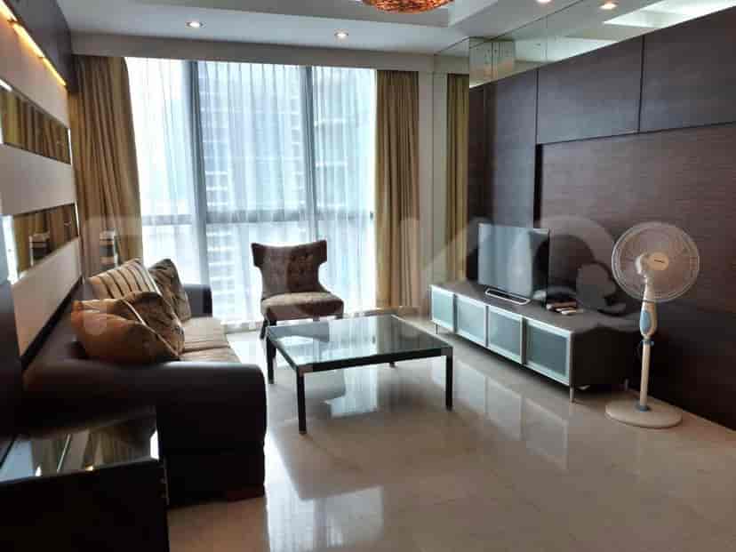 A modern living room featuring a dark brown sofa, glass coffee table, and a TV mounted on a cabinet.