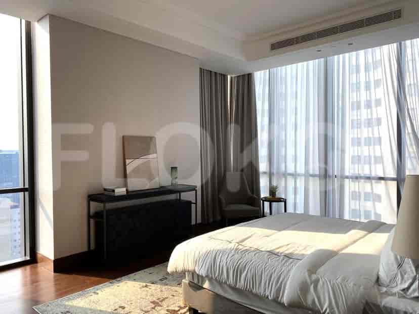 A bedroom with a bed, curtains, and a view of the city.