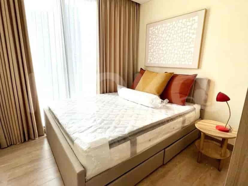 A modern bedroom with a double bed, small side table, and artwork.