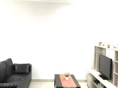 A modern living room featuring a black leather sofa, smart TV, and coffee table.