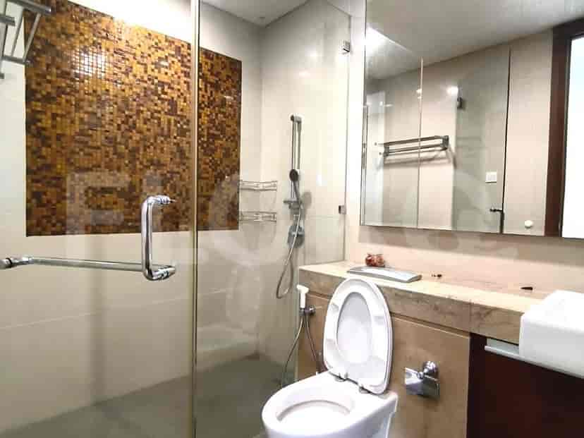 A contemporary bathroom with a glass shower enclosure and mosaic tile accents.