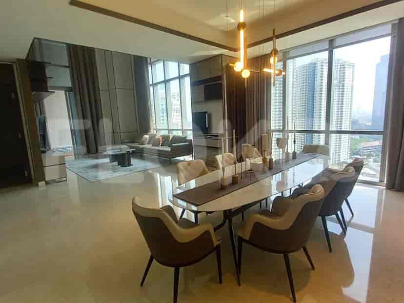 A dining area with a long table, chairs, and a view of the city through large windows.