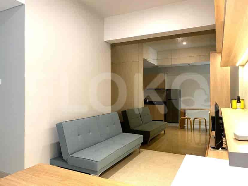 Ruang tamu modern dengan dua sofa abu-abu, dinding kaca reflektif, dan pemandangan dapur.