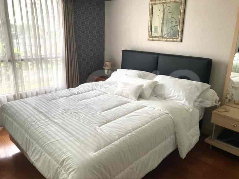 A bedroom with a large bed with white bedding, a nightstand, and wall decor.