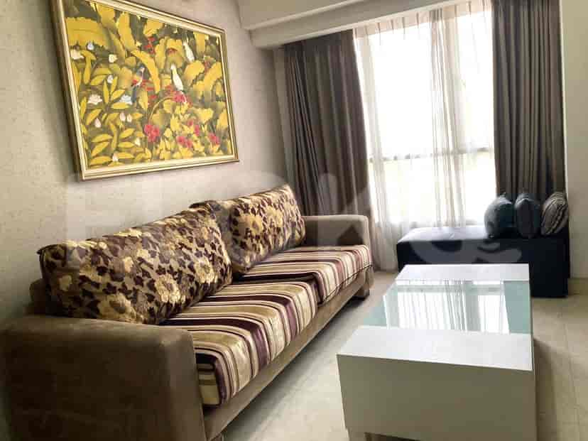 A living room with a floral patterned sofa, painting, and glass-top coffee table.