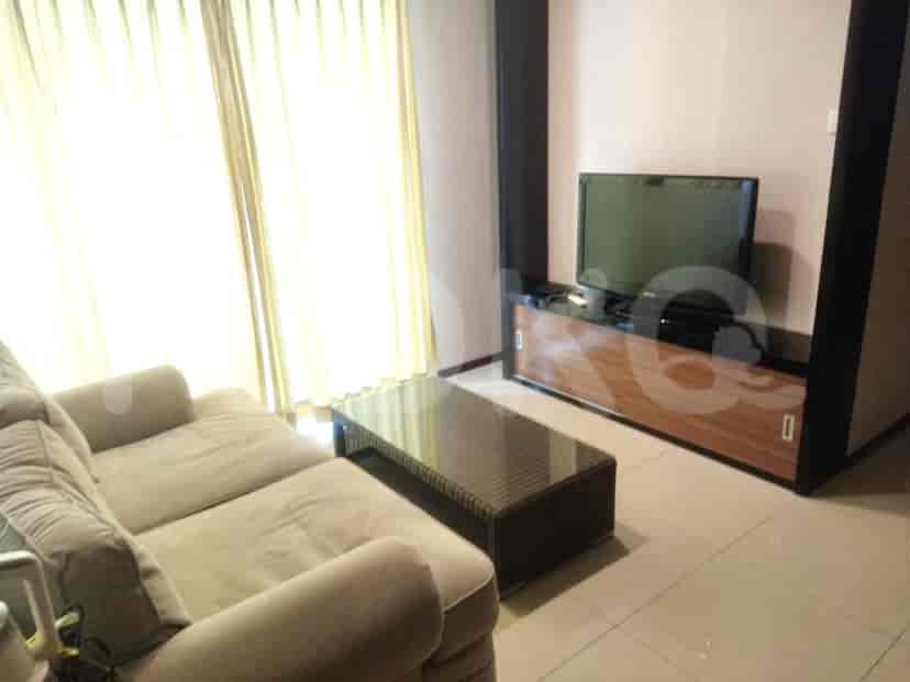 Living room with sofa, coffee table, TV, and window with sheer curtains.