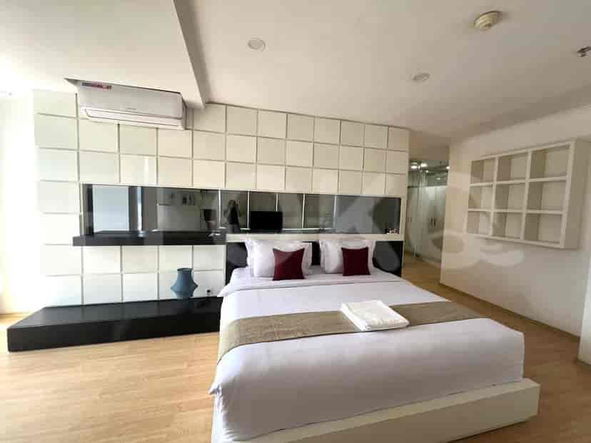 Kamar tidur modern dengan tempat tidur besar dengan bantal dekoratif, aksen cermin, dan desain minimalis.
