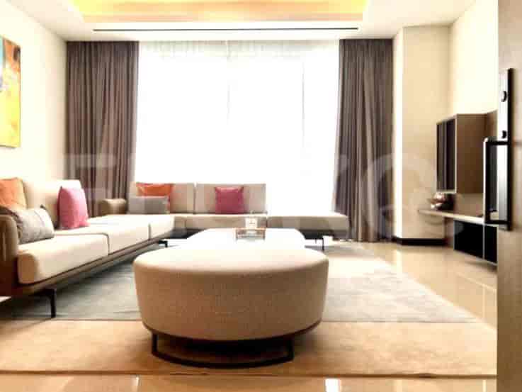 A spacious living room featuring a sectional sofa, a large round ottoman, and a wall-mounted TV.