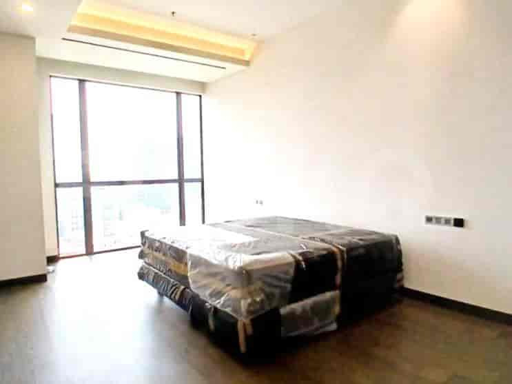 Kamar tidur dengan kasur tertutup dan jendela besar.
