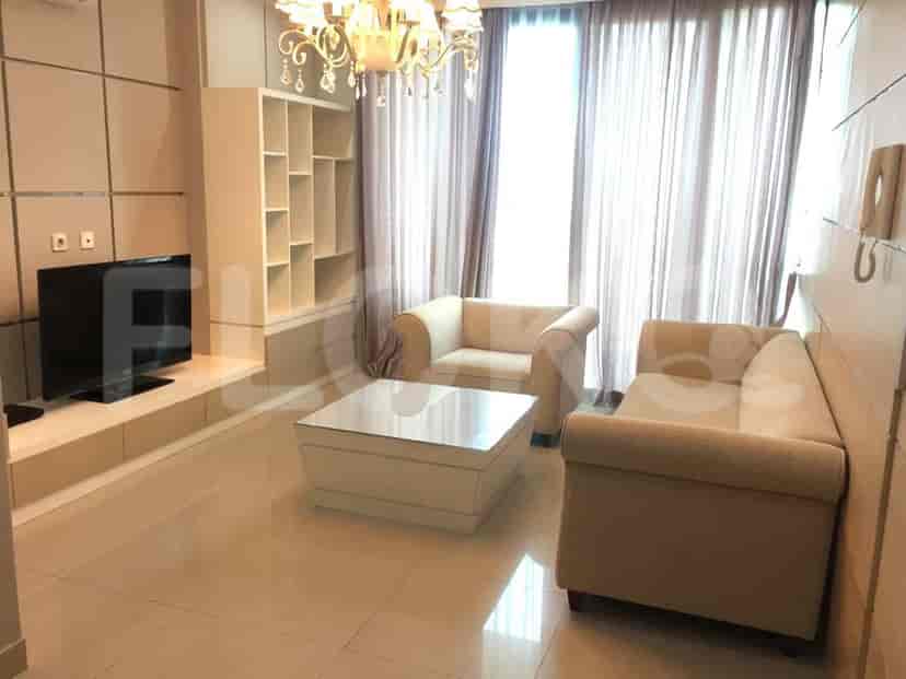 Living room with sofa, TV, shelves, and chandelier.