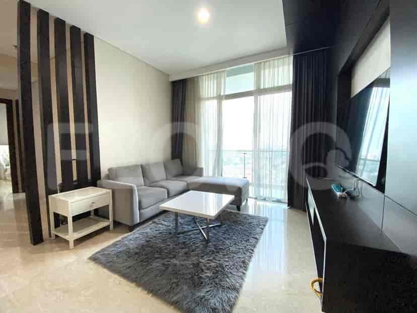 Modern living room with grey sofa, TV, and city view.