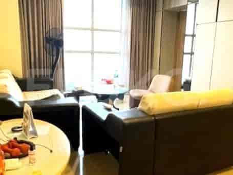 Living room with black sofa, round glass table, fan, and curtains.