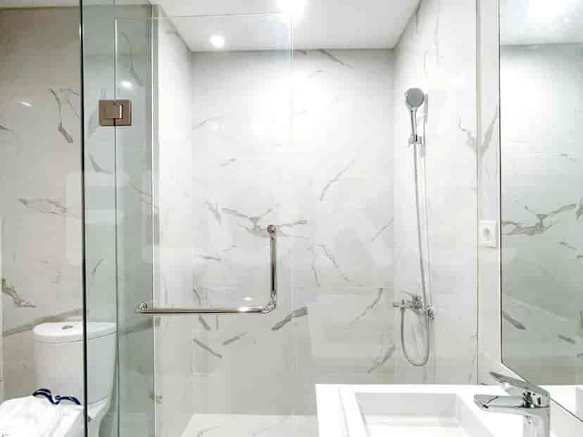 Modern bathroom with white marble tiles, a glass shower enclosure, and a sleek design.
