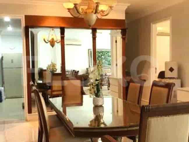 Elegant dining room with a glass-topped table, decorative chandelier, and a view into other rooms.