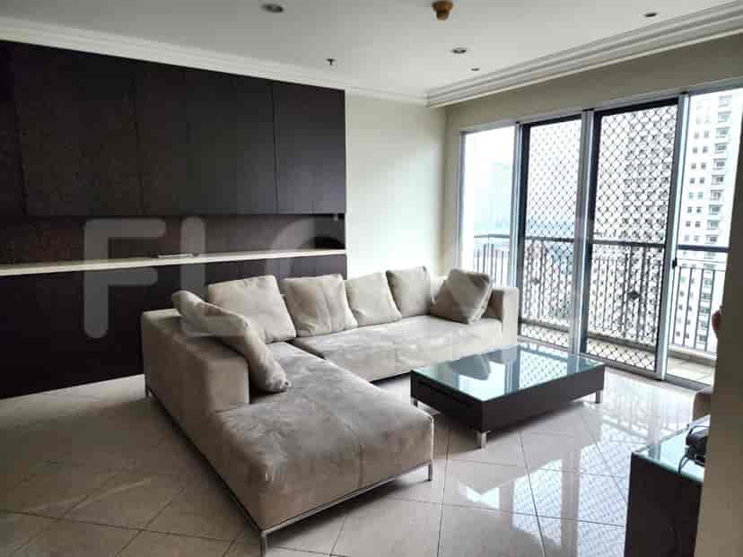 Spacious living room with L-shaped beige sofa, glass coffee table, and a view of a building.