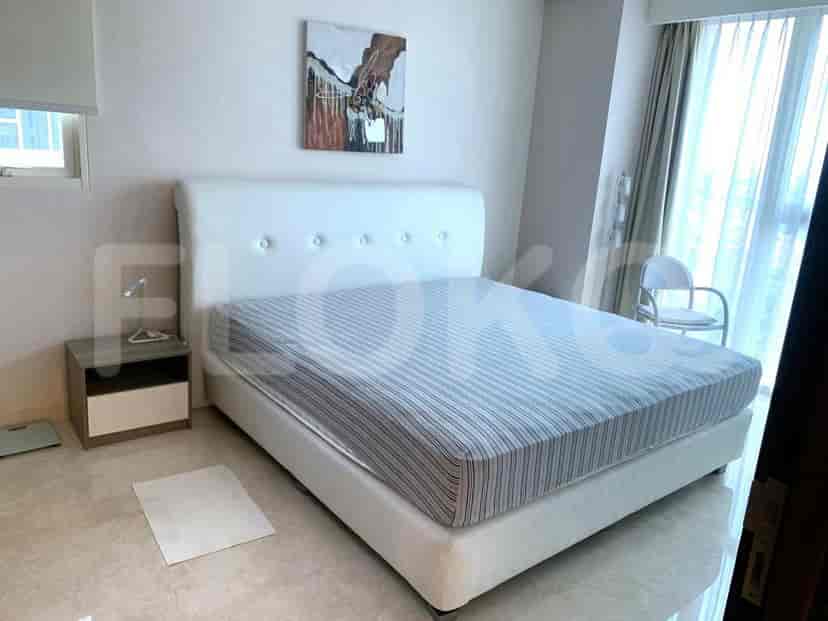 Kamar tidur yang cerah dengan tempat tidur besar, meja samping tempat tidur, dan karya seni.