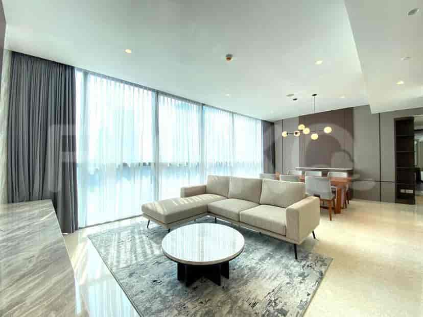 A modern living room with a sectional sofa, round coffee table, and large windows.