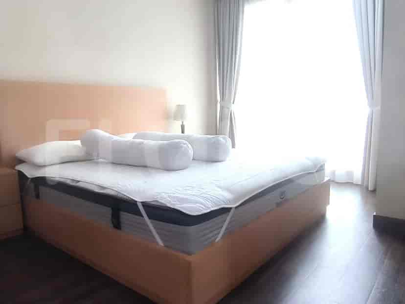 A well-lit bedroom featuring a bed, bedside table, and window.