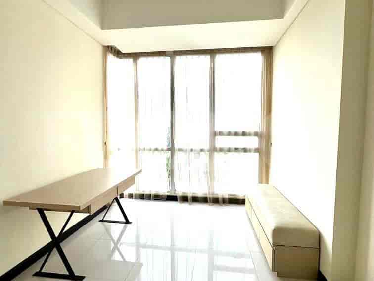 A room with a desk and a bench near large windows.