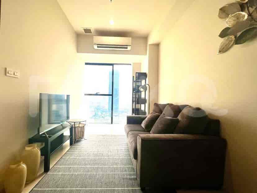 Ruang tamu dengan sofa coklat, TV, dan jendela besar.