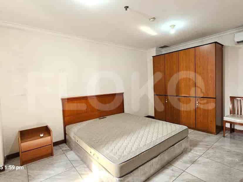 Kamar tidur yang menampilkan tempat tidur, lemari, dan meja samping tempat tidur.