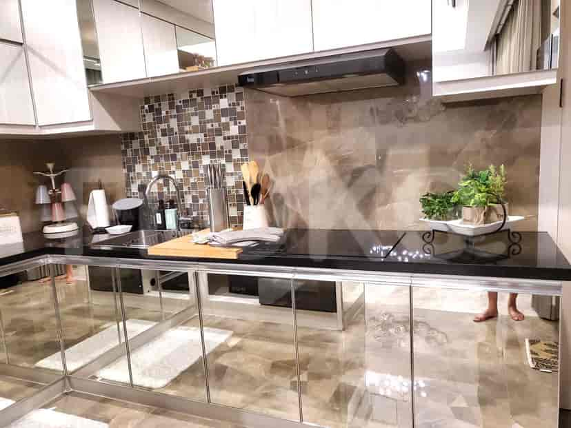 A modern kitchen with mirrored cabinets, a sleek countertop, and essential appliances.