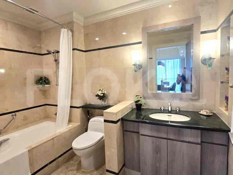 A luxurious bathroom with a bathtub, marble tiling, and a vanity with a large mirror.
