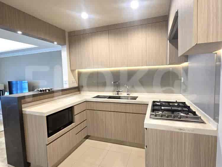A modern kitchen with light wood cabinets, stainless steel appliances, and a marble countertop.