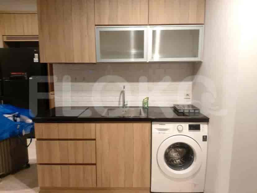 A modern kitchen with wooden cabinets, black countertops, a sink, and a washing machine.