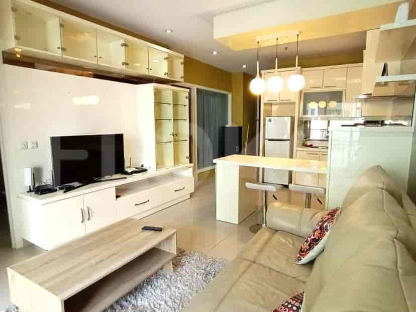 A living room with a TV, cabinets, sofa and a kitchen bar.
